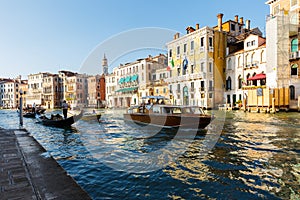 Grand canal, gondolas and pleasure boat. Campanile of Church of Santi Apostoli