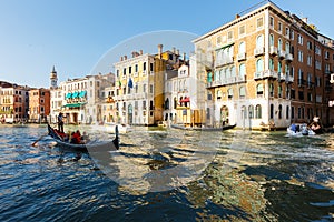 Grand canal, gondolas and pleasure boat. Campanile of Church of Santi Apostoli