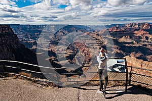 GRAND CANYON, ARIZONA - NOVEMBER 6 2017: Young woman standing on the edge of Grand Canyon taking a photograph. Grand
