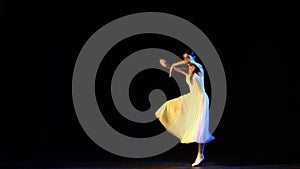 Grand Jete en Tournant. Graceful ballerina in elegant white dress jumping, dancing over dark background. Concept of