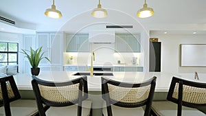Grand modern kitchen having elegant white and tranquil light blue cabinets, gold faucet and marble-centric island. Open