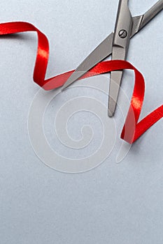 Grand Opening illustrated with scissors and a red ribbon on a gray background