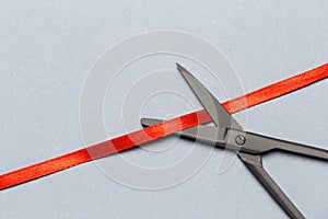 Grand Opening illustrated with scissors and a red ribbon on a gray background