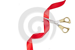 Grand opening. Top view of gold scissors cutting red ribbon on wite background.