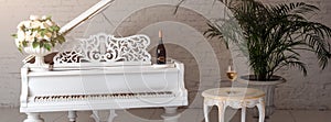 Grand piano in a luxury white classic interior with wine, palms and flowers.