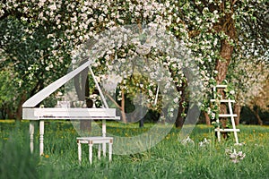 Grand piano and white staircase with romantic decor in spring in a blossoming Apple tree garden