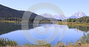 Grand Teton mountains over Snake River scenic pan across water 4K