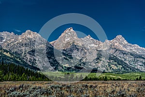 Grand Teton National Park landscape with greenery and high hills against the blue sky in Wyoming