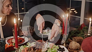 Grandad cuts and serves chicken on table on Christmas Eve, everybody chatting