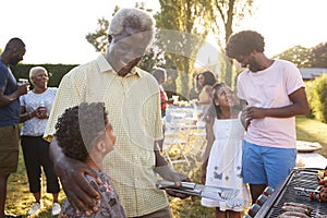 Grandad and dad talking with kids at a family barbecue