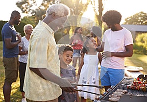 Grandad and grandson grilling at a family barbecue