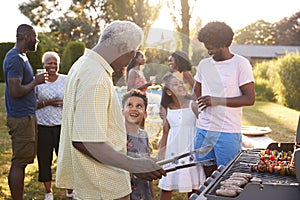 Grandad and grandson talk by the grill at a family barbecue