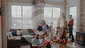 Grandad reading a book with a girl sitting on a chair at Christmas celebration