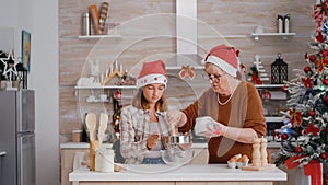 Grandchild helping senior woman preparing homemade traditional cookie dough