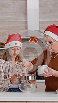 Grandchild helping senior woman preparing homemade traditional cookie dough