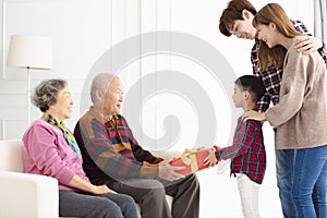 Grandchild with parents giving a gift to grandparents