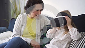 Grandchild is playing with new digital technology of virtual reality simulation glasses.