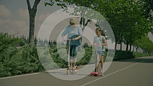 Grandchild teaching grandmom to ride scooter in park