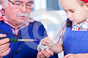 Grandchild touching solder wire to hot soldering iron tip photo