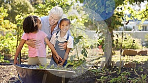 Grandchildren Helping Grandmother Working In Vegetable Garden Or Allotment With Barrow At Home