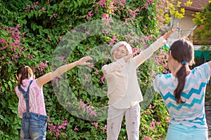 Grandchildren show their grandmother how to dab. Outdoors, summer