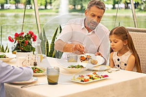 Granddad giving his cute girl some snacks with salmon