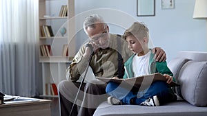 Granddad reading book with boy, doing homework together, upbringing generation