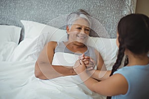 Granddaughter comforting sick grandmother in bed room