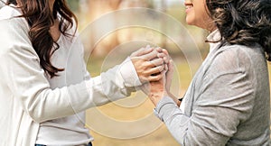 granddaughter consoling her senior grandmother and touching hand when in park