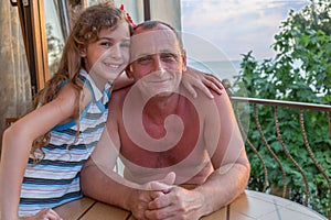 granddaughter embraces grandfather on the balcony