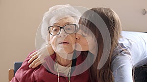 Granddaughter embracing and kissing her grandmother in a geriatric