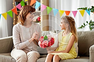 Granddaughter giving grandmother flowers at home