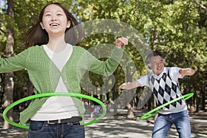 Granddaughter with grandfather having fun and playing with plastic hoop in the park