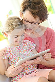 Granddaughter and grandmother playing together on a tablet