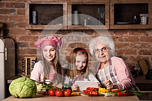 Granddaughter and grandmother with tablet searching recipe