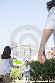 Granddaughter with grandparents playing Frisbee in the park