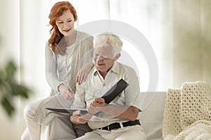 Granddaughter and happy grandfather watching photo album during