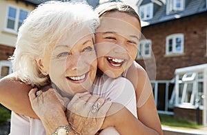 Granddaughter Hugging Grandmother On Bench During Visit To Retirement Home