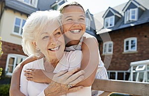 Granddaughter Hugging Grandmother On Bench During Visit To Retirement Home photo