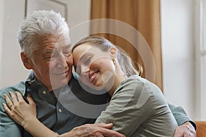 Granddaughter hugging her grandfather in their home.