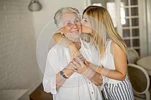 Granddaughter kissing grandmother in the room