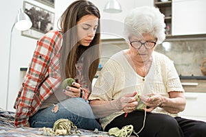 Granddaughter learning how to knit from her grandma