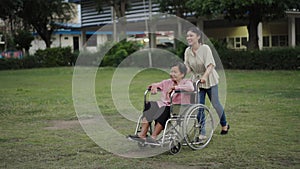 granddaughter pushing senior woman in wheelchair at park