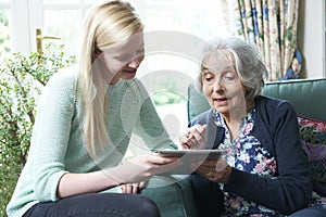 Granddaughter Showing Grandmother How To Use Digital Tablet