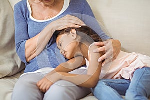 Granddaughter sleeping on grandmothers lap in living room