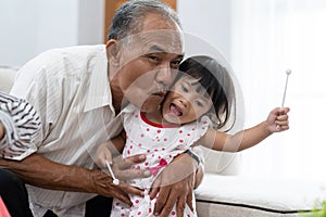 Granddaughter to avoid kiss from her grandfather when enjoying playing a xylophone instrument