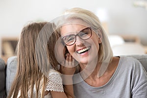 Granddaughter whisper something to granny sharing secret photo