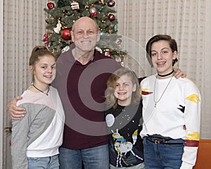 Grandfather and 3 granddaughters standing in front of a Christmas tree
