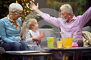 Grandfather amusing his granddaughter, telling story with his arms spread