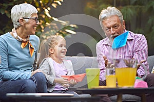 Grandfather amusing his granddaughter, telling story, throwing up and down paper boat